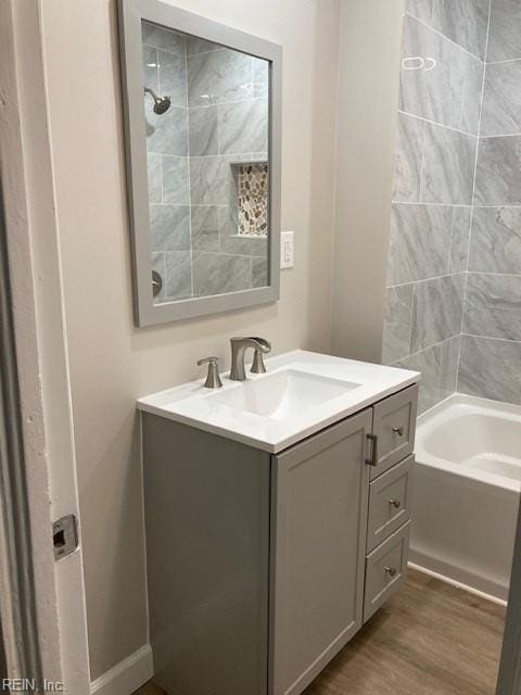 bathroom with tiled shower / bath combo, vanity, and hardwood / wood-style floors