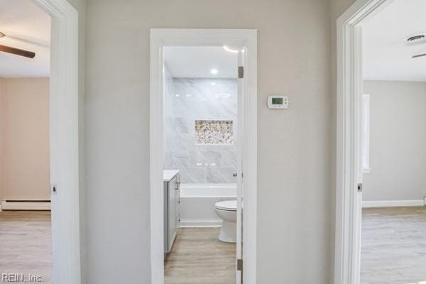 bathroom featuring toilet, vanity, a tub, hardwood / wood-style flooring, and a baseboard heating unit