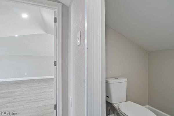 bathroom featuring hardwood / wood-style flooring, toilet, and vaulted ceiling