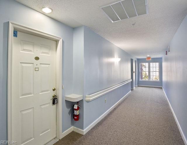 corridor with light colored carpet and a textured ceiling