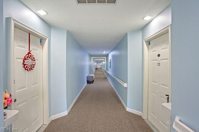 hall with light carpet and a textured ceiling