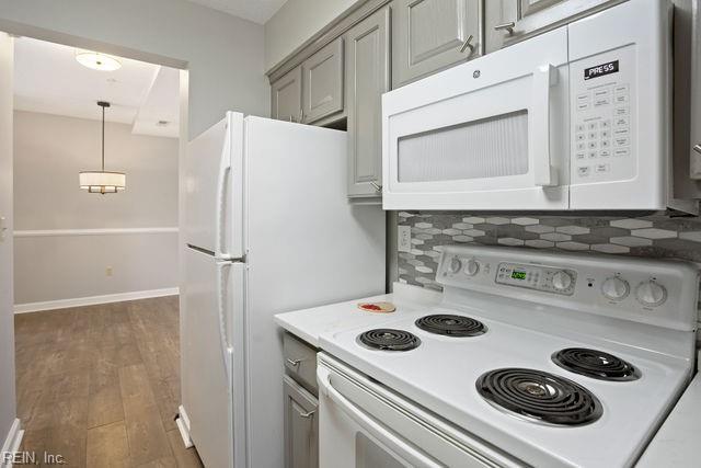 kitchen featuring tasteful backsplash, hanging light fixtures, dark hardwood / wood-style flooring, gray cabinets, and white appliances