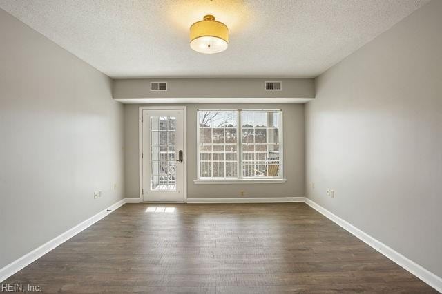 unfurnished room with dark wood-type flooring and a textured ceiling