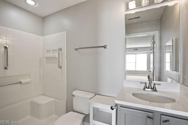 bathroom featuring vanity, toilet, and walk in shower