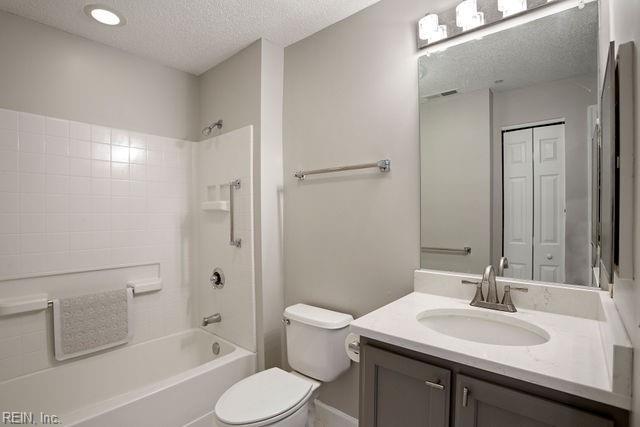 full bathroom with shower / washtub combination, vanity, a textured ceiling, and toilet