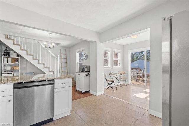 kitchen featuring white cabinets, stainless steel dishwasher, a notable chandelier, light tile patterned floors, and light stone countertops