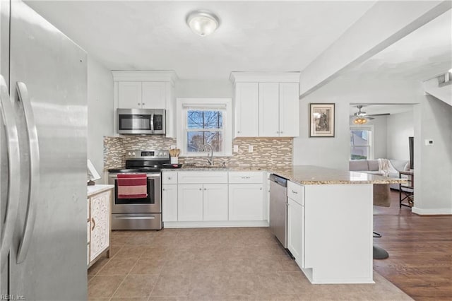 kitchen with sink, a breakfast bar area, white cabinetry, kitchen peninsula, and stainless steel appliances