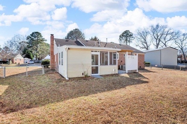 back of property featuring a sunroom and a lawn