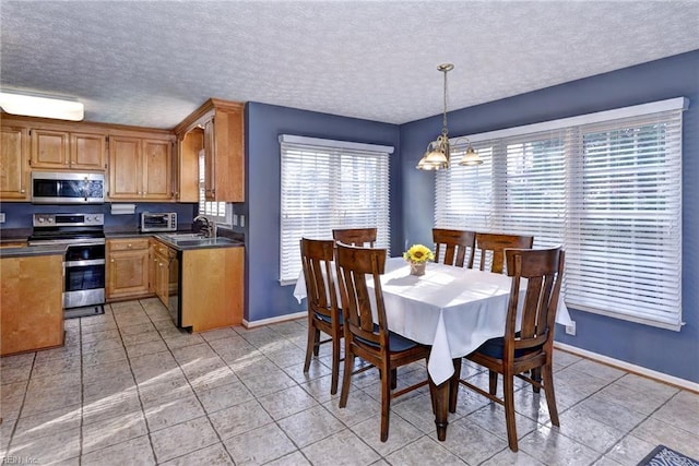 kitchen featuring pendant lighting, sink, a textured ceiling, and appliances with stainless steel finishes