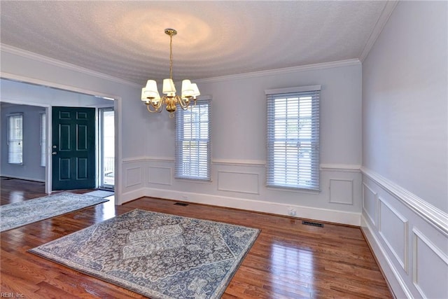 interior space with crown molding, dark hardwood / wood-style floors, a textured ceiling, and a notable chandelier