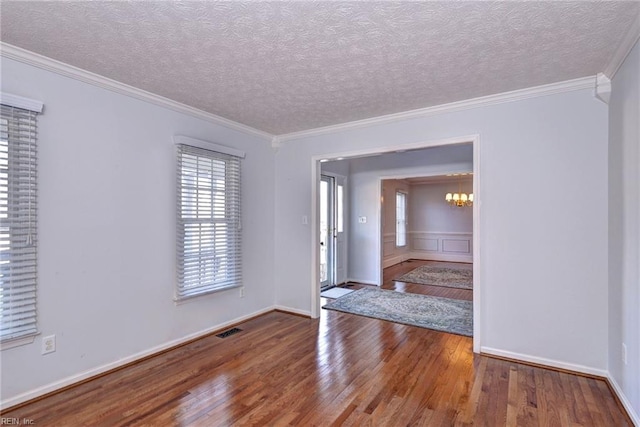 foyer entrance featuring an inviting chandelier, crown molding, wood-type flooring, and a textured ceiling