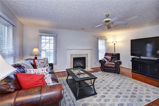 living room with hardwood / wood-style floors, a high end fireplace, plenty of natural light, and a textured ceiling