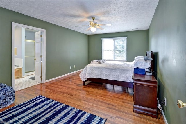 bedroom featuring ensuite bath, a textured ceiling, ceiling fan, hardwood / wood-style floors, and a baseboard heating unit