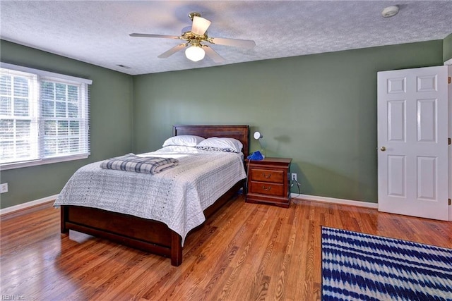 bedroom featuring ceiling fan, hardwood / wood-style flooring, and a textured ceiling