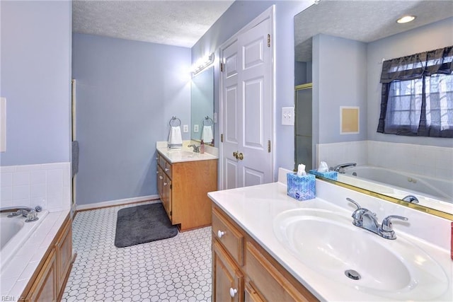 bathroom with tiled tub, vanity, and a textured ceiling