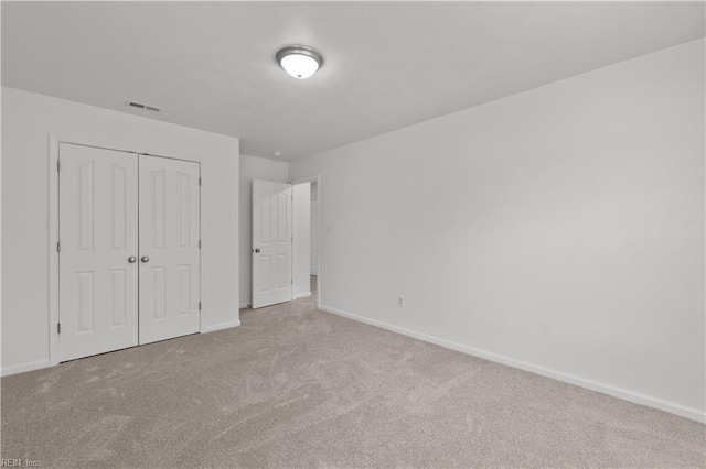 unfurnished bedroom with light colored carpet and a closet