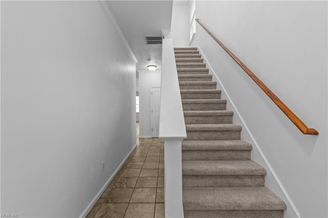 stairway with ornamental molding and tile patterned floors