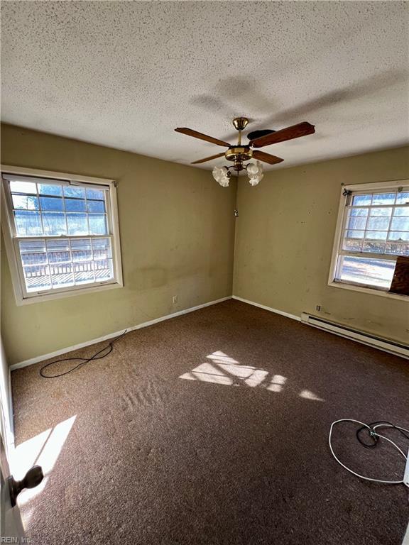 carpeted spare room featuring ceiling fan, a baseboard heating unit, and a textured ceiling