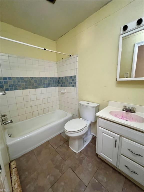 full bathroom with tiled shower / bath combo, vanity, tile patterned floors, and toilet