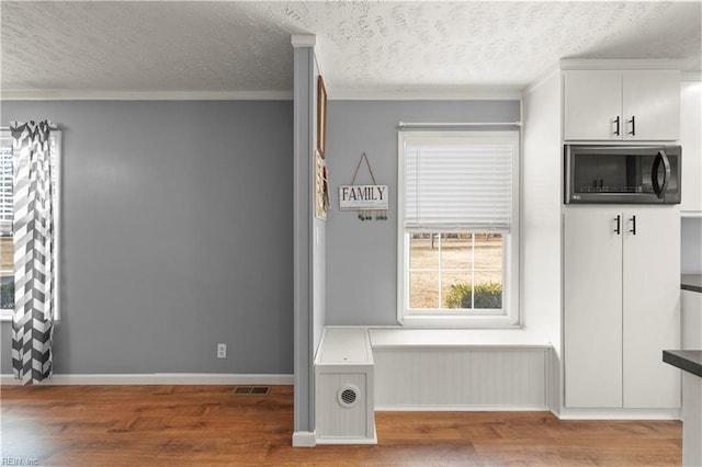 mudroom featuring wood-type flooring, ornamental molding, and a textured ceiling