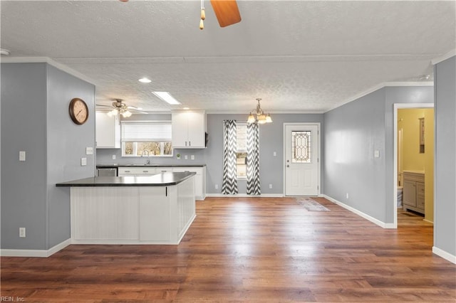 kitchen with white cabinetry, dark hardwood / wood-style flooring, ceiling fan with notable chandelier, decorative light fixtures, and kitchen peninsula