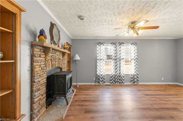 living room with crown molding, hardwood / wood-style floors, a textured ceiling, and a wood stove