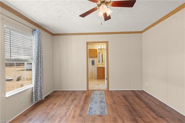 empty room with crown molding, hardwood / wood-style floors, and a textured ceiling