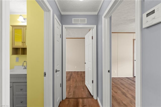 hallway featuring sink, hardwood / wood-style floors, and a textured ceiling