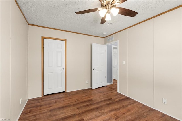 unfurnished bedroom with crown molding, dark hardwood / wood-style floors, and a textured ceiling