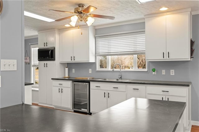 kitchen featuring sink, a textured ceiling, ceiling fan, beverage cooler, and white cabinets