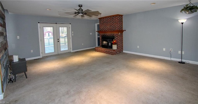 unfurnished living room with french doors, ceiling fan, a fireplace, and carpet