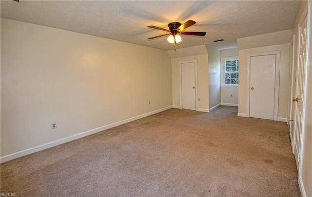 unfurnished bedroom featuring ceiling fan, light colored carpet, and a textured ceiling