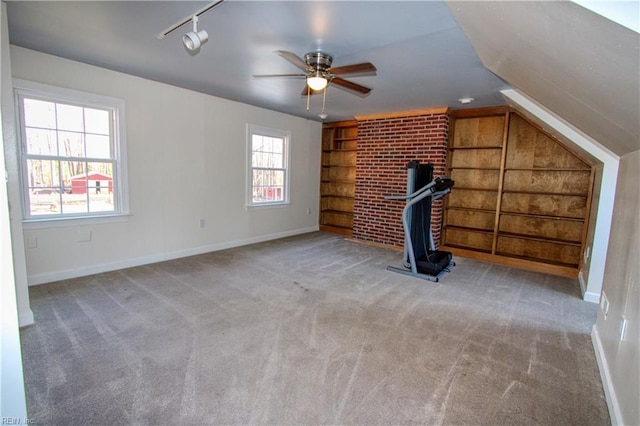 interior space featuring light carpet, built in shelves, vaulted ceiling, and a healthy amount of sunlight