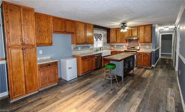 kitchen featuring backsplash, a kitchen breakfast bar, stainless steel appliances, a center island, and dark hardwood / wood-style flooring