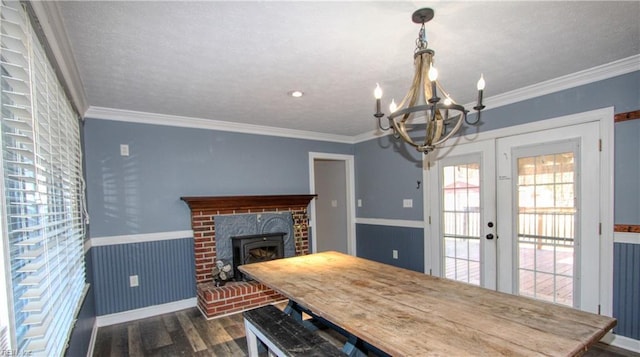 dining room featuring ornamental molding, a brick fireplace, an inviting chandelier, and dark hardwood / wood-style flooring