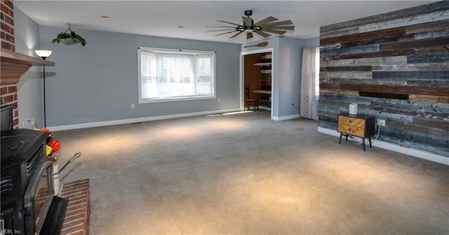 carpeted living room featuring ceiling fan, a wood stove, and wooden walls