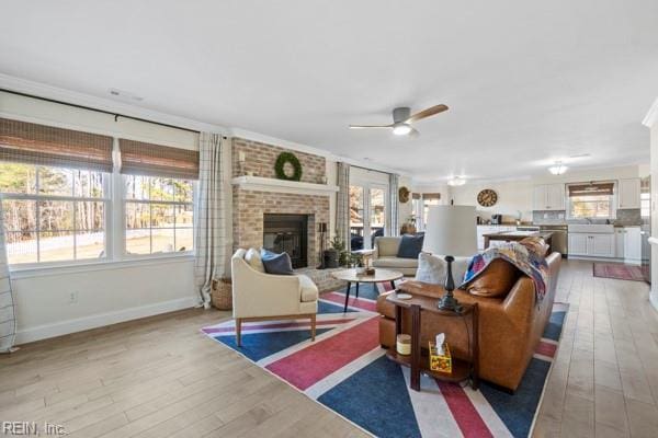 living room with ceiling fan, a fireplace, and light wood-type flooring