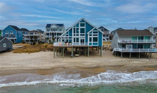 rear view of house with a water view and a beach view