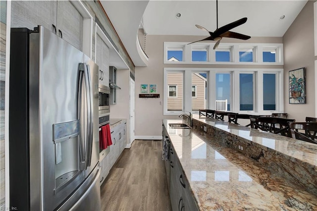 kitchen with light stone counters, sink, high vaulted ceiling, and appliances with stainless steel finishes