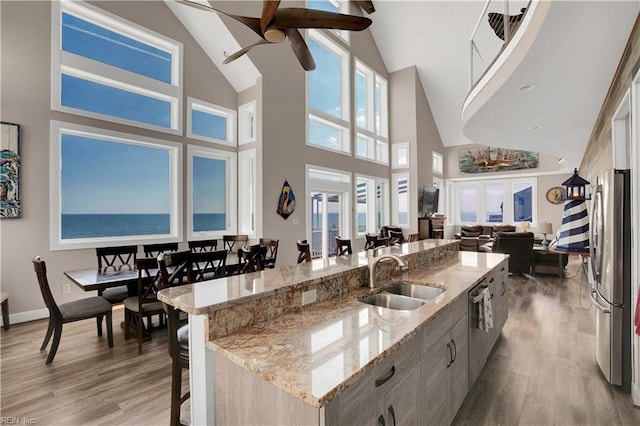 kitchen with a kitchen bar, sink, a center island with sink, light hardwood / wood-style flooring, and appliances with stainless steel finishes