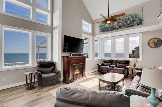 living room with ceiling fan, high vaulted ceiling, and light hardwood / wood-style flooring