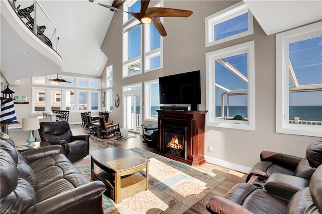 living room with hardwood / wood-style flooring, a towering ceiling, and ceiling fan