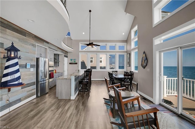 kitchen with light stone countertops, stainless steel refrigerator with ice dispenser, a water view, and a healthy amount of sunlight