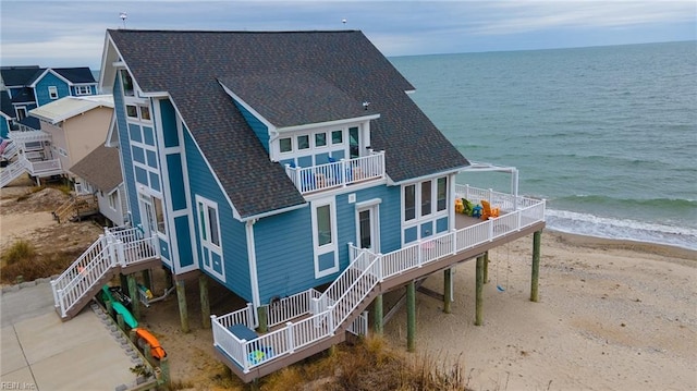 back of property featuring a beach view and a water view