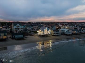 aerial view at dusk featuring a water view and a view of the beach