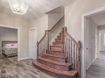 staircase featuring wood-type flooring and a chandelier