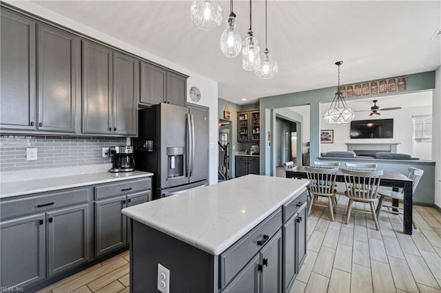 kitchen with gray cabinetry, hanging light fixtures, a center island, and stainless steel refrigerator with ice dispenser