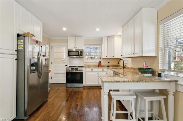 kitchen featuring a breakfast bar, sink, white cabinetry, kitchen peninsula, and stainless steel appliances