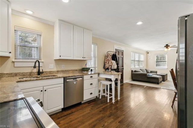 kitchen with sink, stainless steel appliances, ornamental molding, light stone countertops, and white cabinets