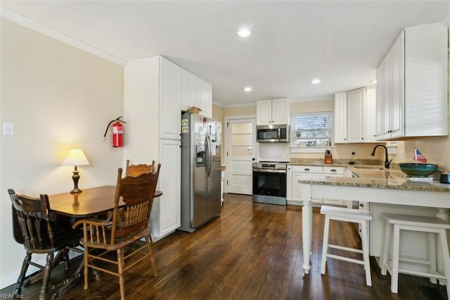 kitchen featuring appliances with stainless steel finishes, sink, white cabinets, dark hardwood / wood-style flooring, and crown molding